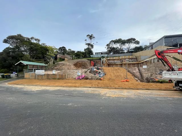 Sloping residential construction site with excavation and retaining works underway