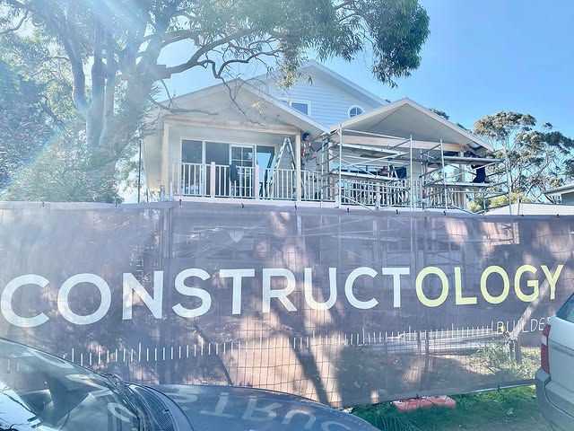 Constructology home under construction behind branded site fencing