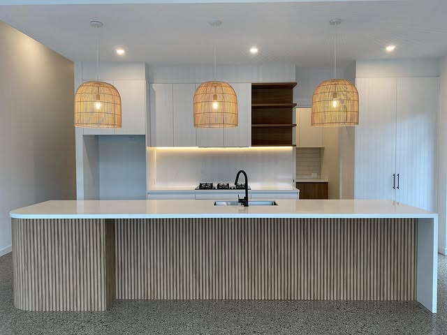 Finished kitchen with fluted island cabinetry and woven pendant lights