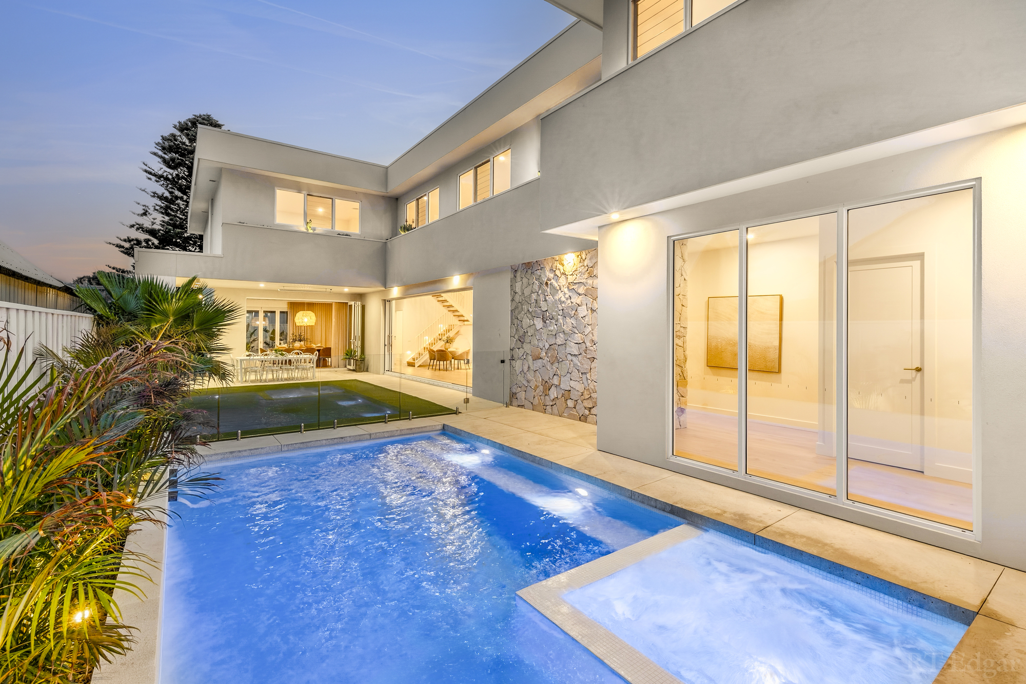 Illuminated rear courtyard and swimming pool at dusk