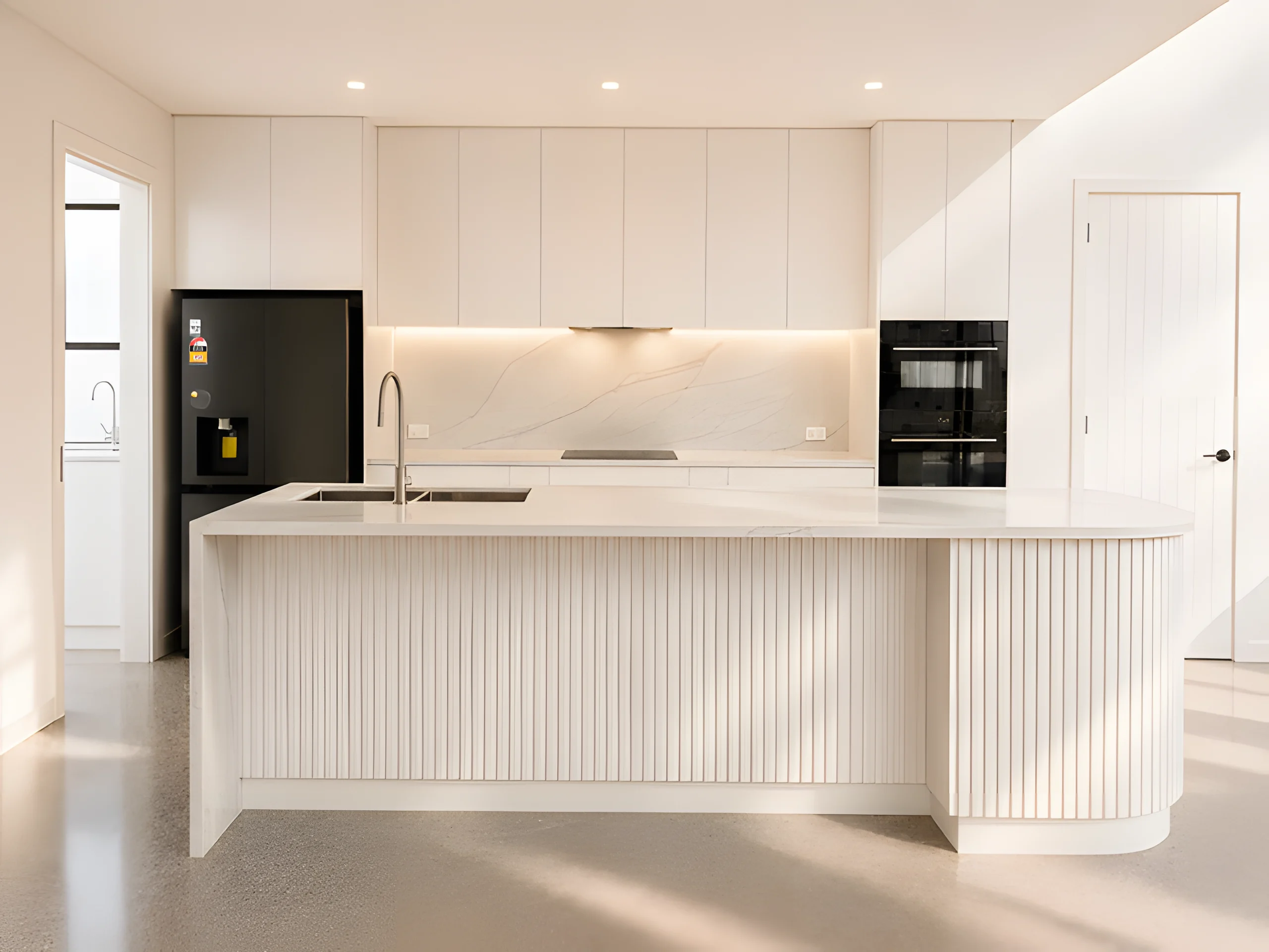 Midden Terrace kitchen with a curved fluted island and pale stone finishes